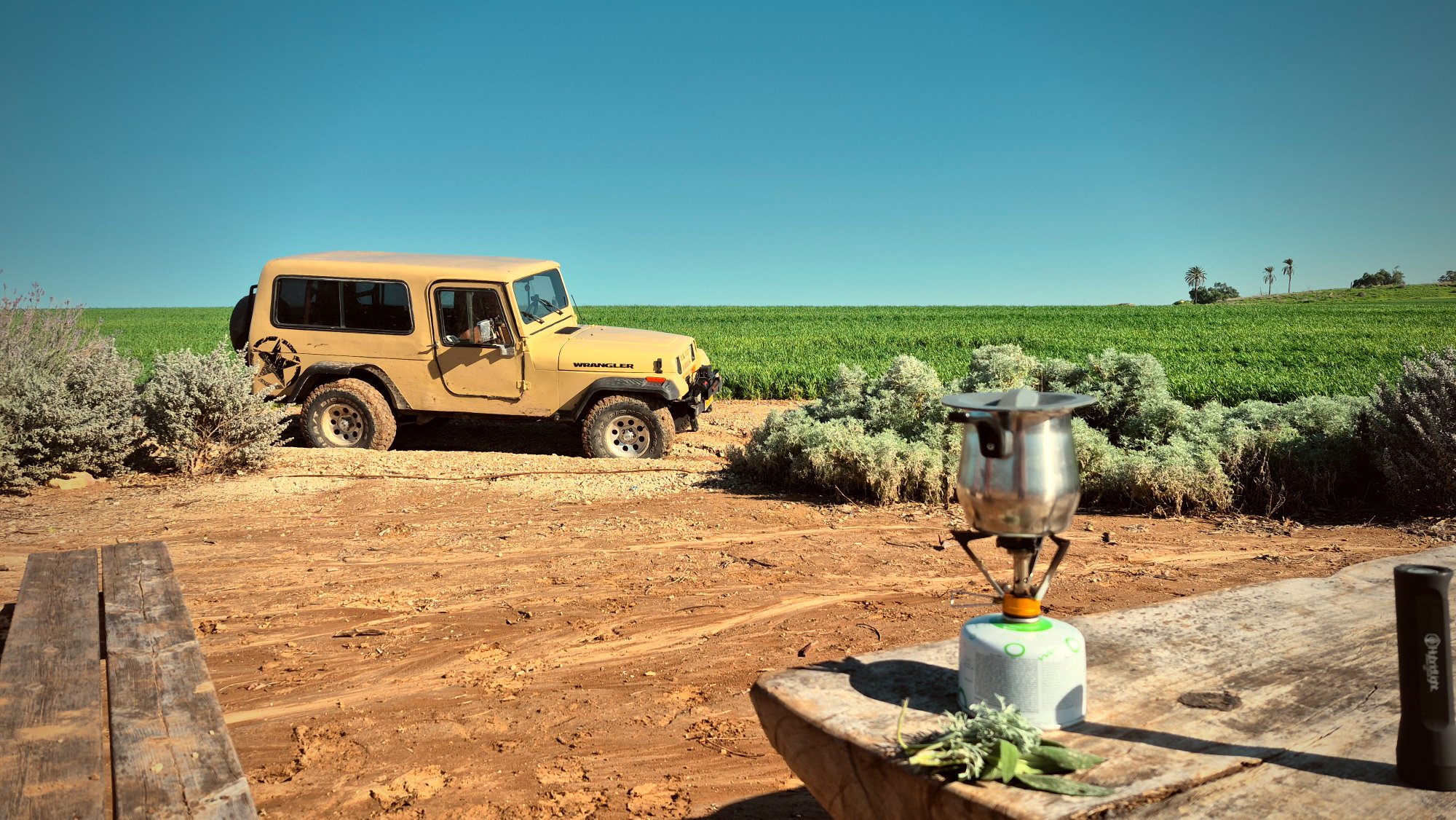 Coffee boiled on the tailgate, jeep by a green field